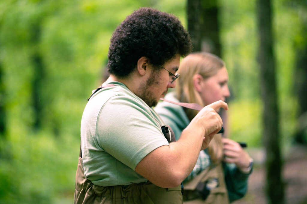 Jackson and another student stand in the woods.