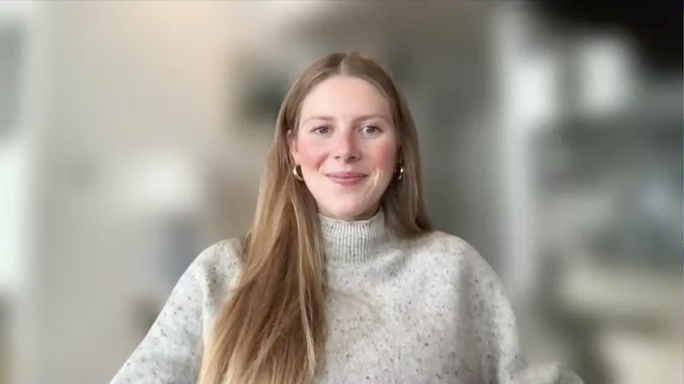 Allie smiles on a video call. Her background is blurred.