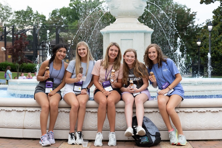 Sydney and four other young women smile as they sit on the edge of Harrison Fountain, ice cream cones in hand.