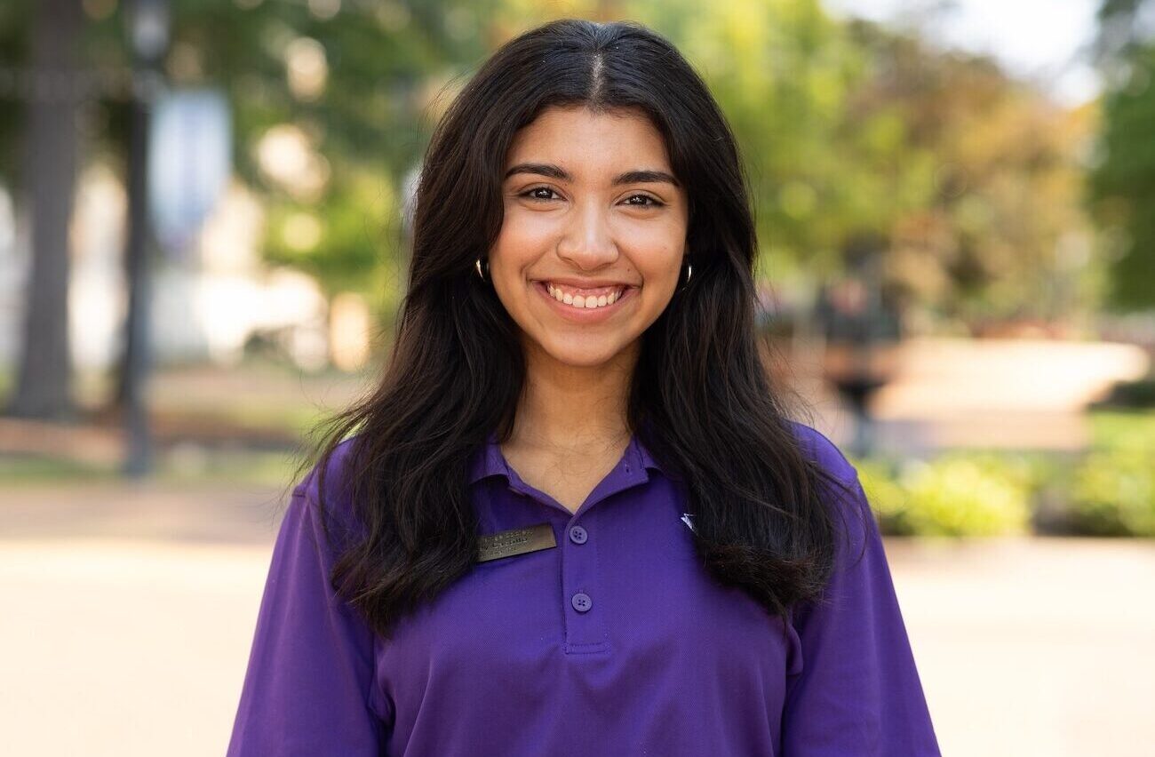 Sydney Castillo smiles as she poses outdoors on UNA's campus.