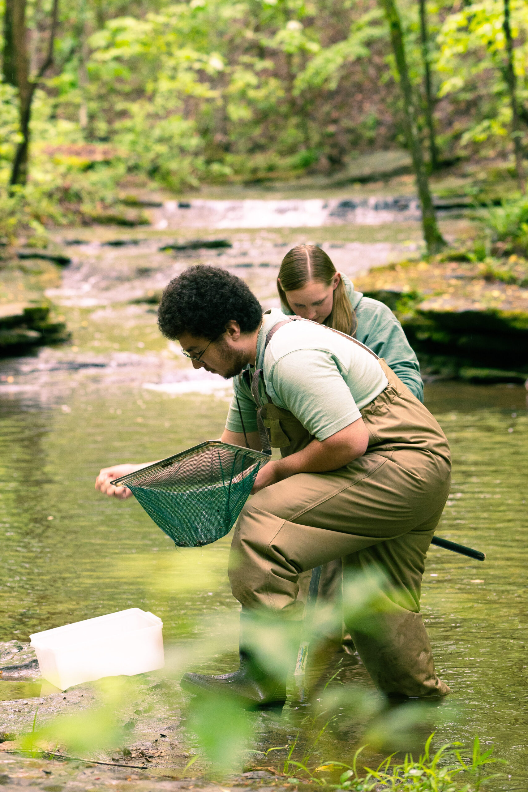 Jackson, net in hand, explores a river with a fellow UNA student.