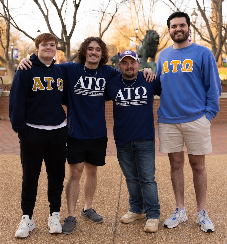 Oakley and three other young men from Alpha Tau Omega smile as they pose outdoors on UNA's campus.