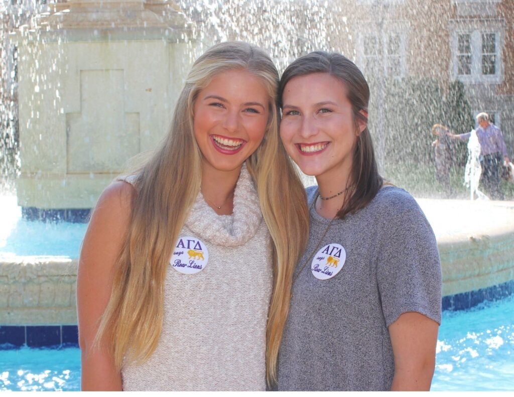 Allie and another student smile as they pose in front of the University of North Alabama's Harrison Fountain.